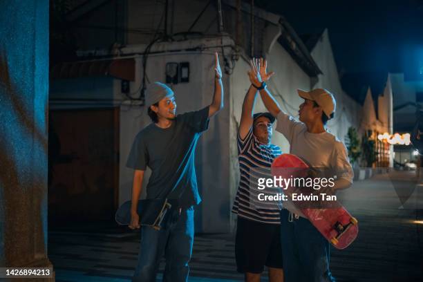 diversifizieren sie junge männer high five feiern stunt-leistung in der hintergasse bei nacht - welcome back stock-fotos und bilder