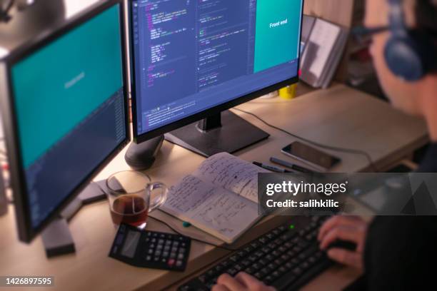 a male programmer coding in the night time while listening music with stereo headphones. front end development concept. - low code stock pictures, royalty-free photos & images