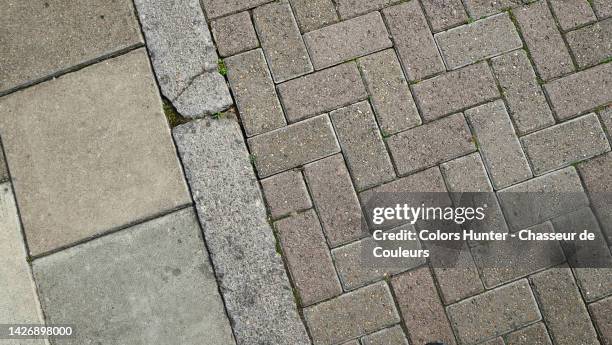 close-up of a pavement and cobbled street separated by a stone curb in london, england, uk - rinnstein stock-fotos und bilder