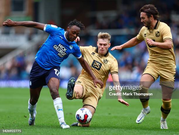 Ricky Jade-Jones of Peterborough United is challenged by Lewis Cass of Port Vale as Dan Jones supports during the Sky Bet League One between...