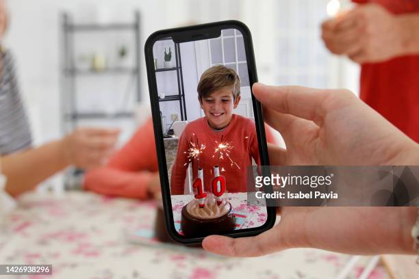 woman using phone to photograph kid at birthday - boy pre adolescent phone hand foto e immagini stock