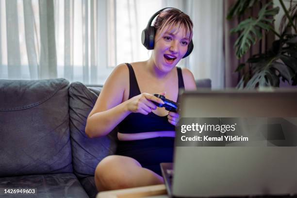 young gamer playing computer game on laptop - one woman only videos stock pictures, royalty-free photos & images