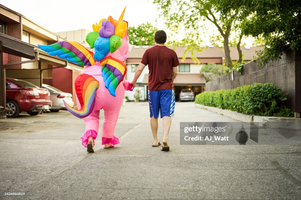 Mann mit einer Person im Einhorn-Kostüm geht im Freien