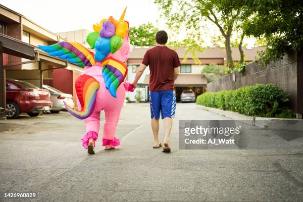 uomo con una persona in costume dell'unicorno che cammina all'aperto - costume foto e immagini stock