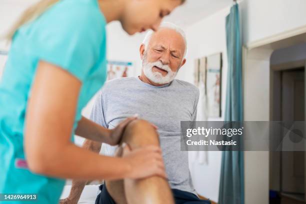 senior man on a manual therapy making a pain face - osteoporosis stock pictures, royalty-free photos & images