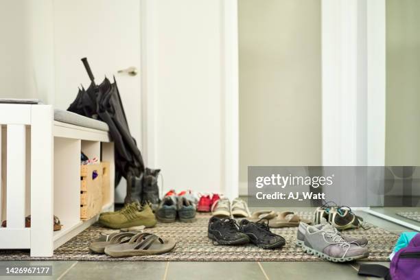 shoes scattered on door mat at home - corridor stockfoto's en -beelden