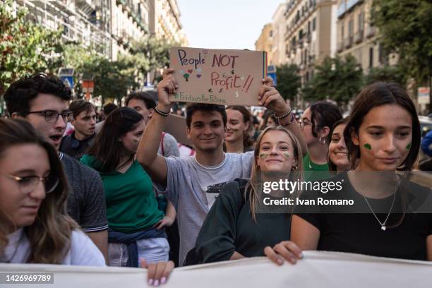 People show signs and flags with environmental slogans during the climate march of the Fridays for Future movement on September 23, 2022 in Naples,...