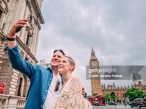 cute caucasian male and female taking selfies together while in london, england in front of big ben clock tower - big ben selfie stock pictures, royalty-free photos & images