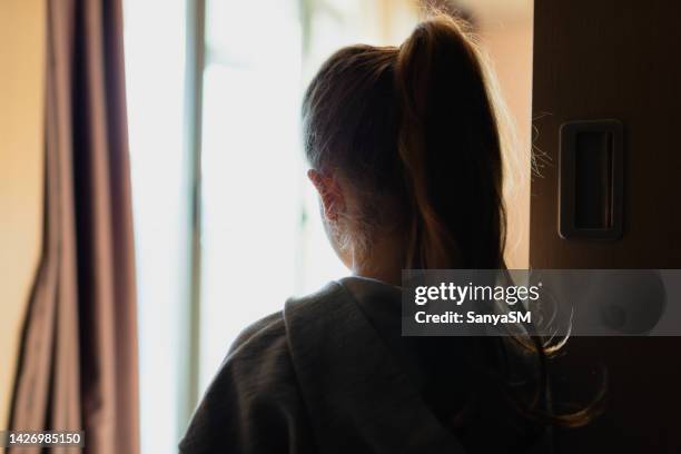 looking trough the window - sad girl standing stock pictures, royalty-free photos & images