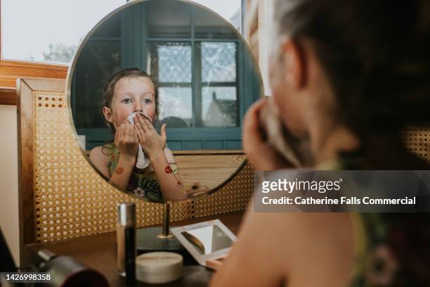 a mischievous little girl washes make-up off her face with a wipe - papiertaschentuch stock-fotos und bilder