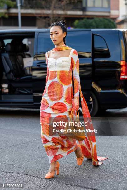 Guest wears white dress with red dots, rust brown bag outside Sunnei during the Milan Fashion Week - Womenswear Spring/Summer 2023 on September 23,...