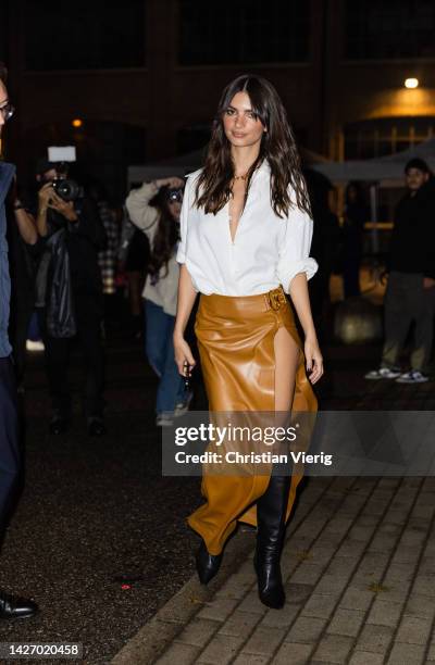 Emily Ratajkowski wears brown skirt with slit, black boots, white button shirt outside Bally during the Milan Fashion Week - Womenswear Spring/Summer...