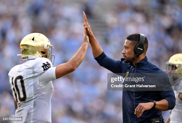 Head coach Marcus Freeman high-fives Drew Pyne of the Notre Dame Fighting Irish after a touchdown drive against the North Carolina Tar Heels during...