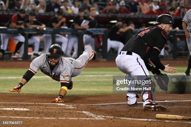 Brandon Crawford of the San Francisco Giants scores on a single by Jason Vosler as Carson Kelly of the Arizona Diamondbacks waits for the throw from...