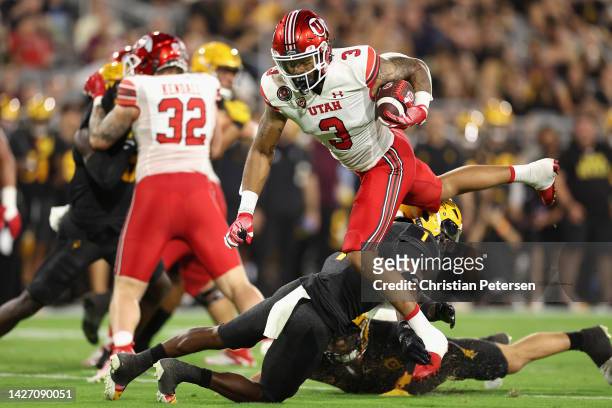 Runningback Ja'Quinden Jackson of the Utah Utes leaps over defensive back Jordan Clark of the Arizona State Sun Devil during the first half of the...
