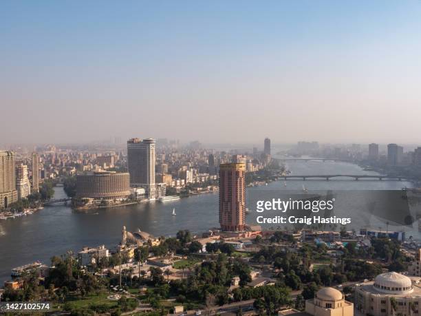 aerial view of south downtown cairo cityscape and city life with views over the river nile, al manial  rhoda island and cairo university bridge in the distance. golden hour sunset light conditions creating glow and casting shadows - road to war in middle east and north africa stock-fotos und bilder