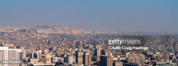 panoramic aerial view of downtown cairo cityscape and city life. golden hour sunset light conditions creating glow and casting shadows - road to war in middle east and north africa stock-fotos und bilder