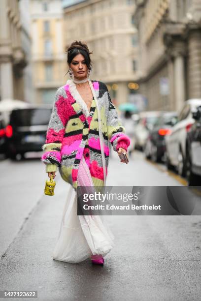Angela Rozas Saiz wears oversized white pearls and purple stones earrings, a white tulle with embroidered polka dots print pattern scarf, a neon pink...