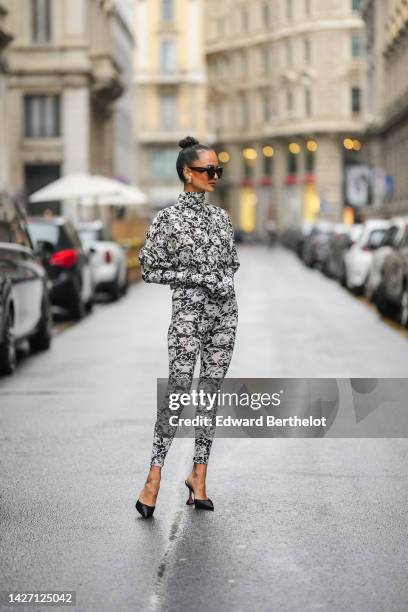 Anna Rosa Vitiello wears black large sunglasses from Loewe, gold and rhinestones large earrings, a black and white cat print pattern turtleneck...