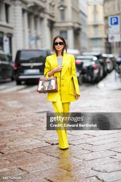 Heart Evangelista wears black sunglasses, silver and pink diamonds earrings, a gray cropped top, a yellow shiny leather / flared slit long sleeves...