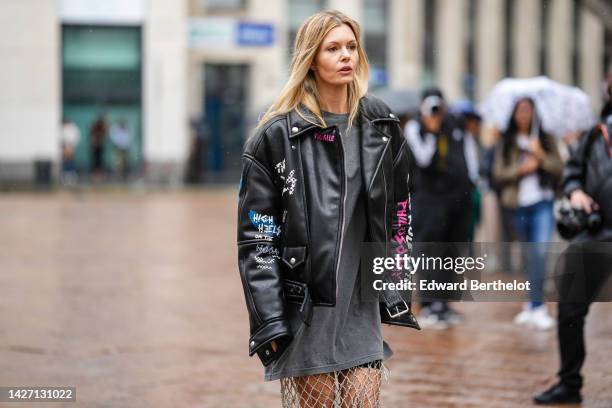 Elizabeth Sulcer wears a dark gray oversized shirt, black cyclist shorts, a silver rhinestones checkered knees skirt, a black shiny leather with...