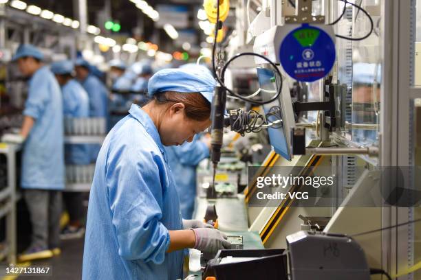 Workers assemble the intelligent central control navigation system of cars at Jiangsu Beidou Xingtong Automotive Electronics Co., Ltd. On September...