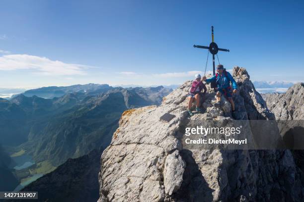 two climber on the summit cross on top of watzmann stock - berchtesgaden stock pictures, royalty-free photos & images