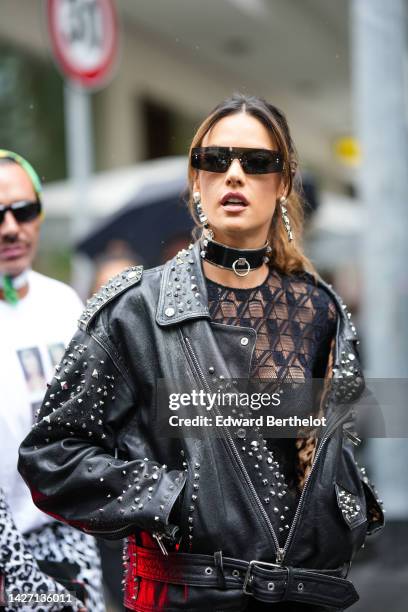 Alessandra Ambrosio wears black sunglasses from Dolce & Gabbana, a black shiny varnished leather large necklace from Dolce & Gabbana, a crystal /...