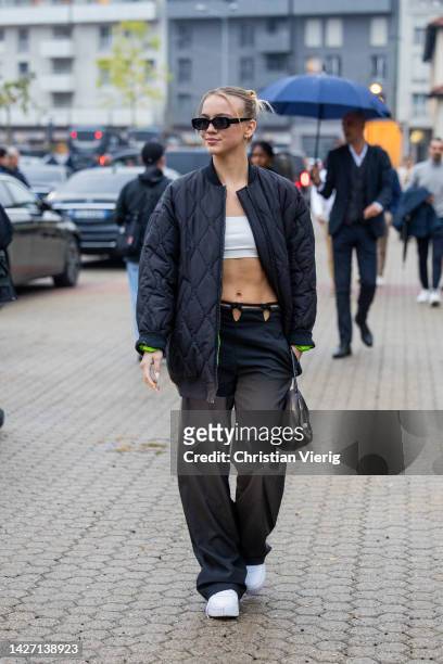 Guest wears black quilted bomber jacket, cut out ants, white cropped top outside Bally during the Milan Fashion Week - Womenswear Spring/Summer 2023...