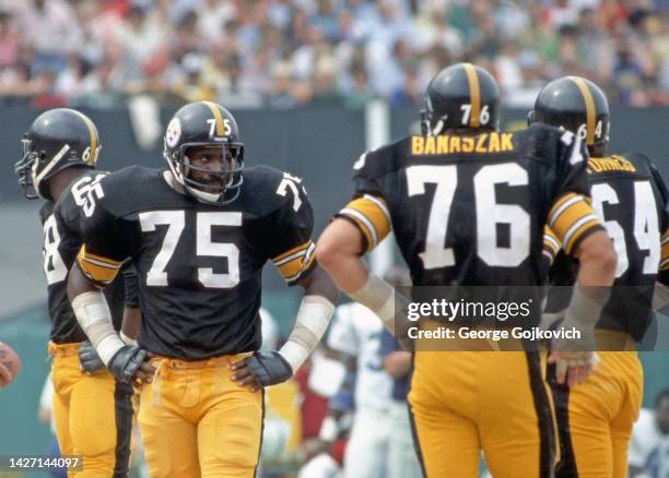 Defensive lineman Joe Greene of the Pittsburgh Steelers looks on from the field as he stands near defensive linemen L.C. Greenwood, John Banaszak and...