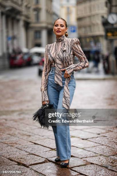 Guest wears diamonds earrings, a beige with black chain print pattern turtleneck / long sleeves / shoulder-pads silk blouse, blue faded high waist...