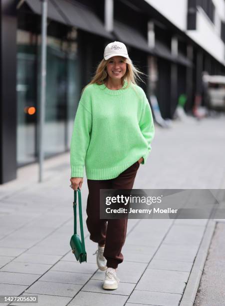 Yasmin von Schlieffen-Nannen is seen wearing a beige cap from Ritz Paris x Frame, green wool knit COS sweater, brown jogger pants from Zara, green...