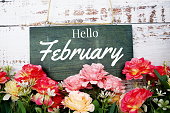 Hello February typography text decorate with flower on wooden background