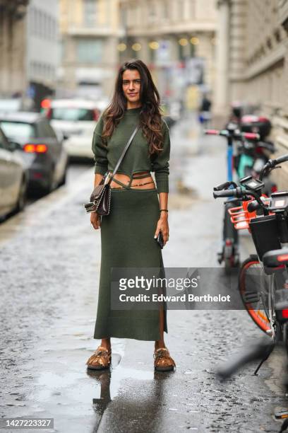 Guest wears a khaki long sleeves laces waist wool pullover, a matching khaki lace waist long wool skirt, a black shiny leather crossbody bag, rings,...