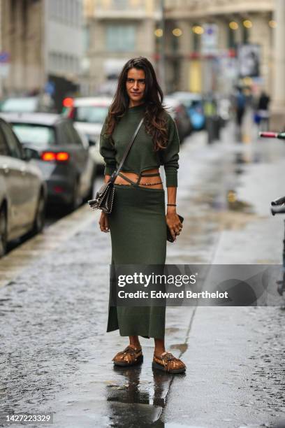 Guest wears a khaki long sleeves laces waist wool pullover, a matching khaki lace waist long wool skirt, a black shiny leather crossbody bag, rings,...