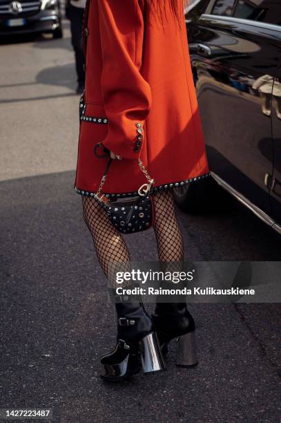 Guest wearing a red coat, black shoes, and a black handbag outside Gucci, during the Milan Fashion Week - Womenswear Spring/Summer 2023 on September...