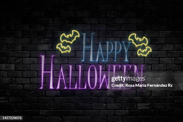 happy halloween message in neon lights  on dark background. - halloween font stock pictures, royalty-free photos & images