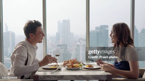 sweet asian couple having a romantic dinner and spending time together in restaurant. celebrating valentine's day - rooftop dining foto e immagini stock