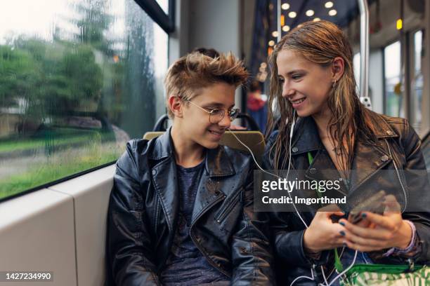 teenagers using public transport - sharing headphones stock pictures, royalty-free photos & images