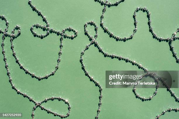 silver and gold beads on a green background. universal holiday background. - chaîne photos et images de collection