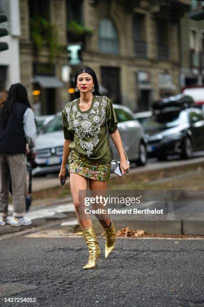 Guest wears gold and rhinestones large pendant logo earrings from Dolce & Gabbana, a khaki with embroidered large crystal jewels large t-shirt from...