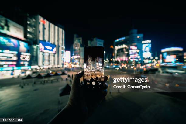 close up of man's hands making a photo with mobile phone of ximending shopping district in taipei taiwan, the most popular night life in taipei - ximen stock pictures, royalty-free photos & images