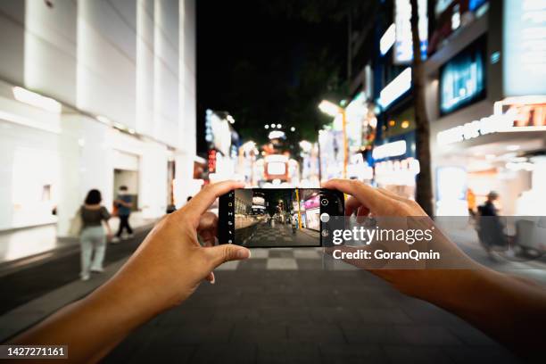 close up of woman's hands making a photo with mobile phone of ximending shopping district in taipei taiwan, the most popular night life in taipei - ximen stock pictures, royalty-free photos & images