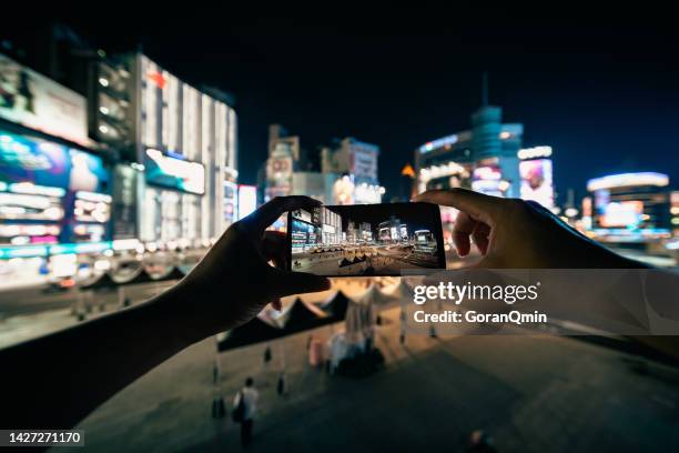 close up of woman's hands making a photo with mobile phone of ximending shopping district in taipei taiwan, the most popular night life in taipei - ximen stock pictures, royalty-free photos & images