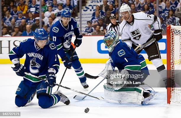 Dan Hamhuis of the Vancouver Canucks clears the loose puck after blocking a shot as goalie Roberto Luongo and Ryan Kesler of the Vancouver Canucks...