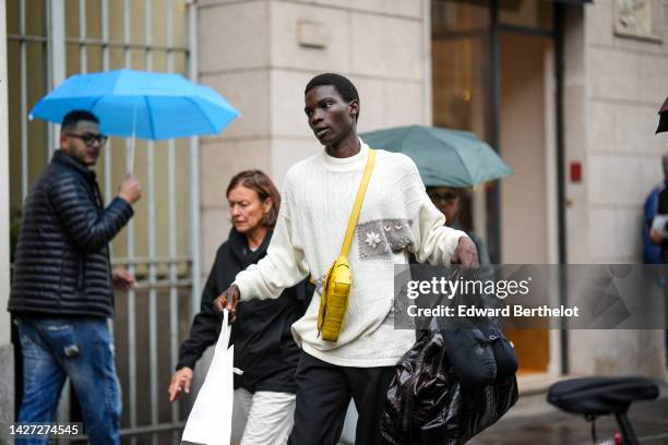 Guest wears a white latte embossed pattern and gray yoke oversized pullover, black suit pants, a yellow shiny leather Cassette crossbody bag from...