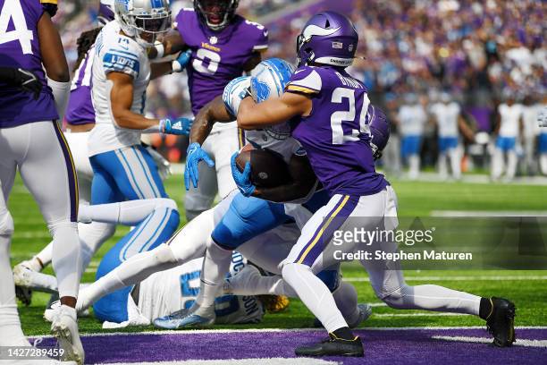 Running back Jamaal Williams of the Detroit Lions scores a touchdown in the first quarter as safety Camryn Bynum of the Minnesota Vikings tries to...