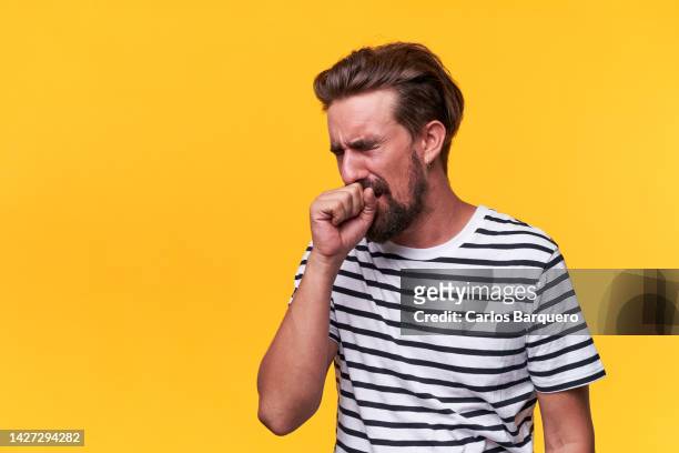 copy space photo of sick man coughing, standing by a yellow background. - cough stock-fotos und bilder
