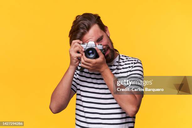 close up portrait of caucasian photographer using an analog camera to take a photo when captured. - pointing at camera - fotografias e filmes do acervo