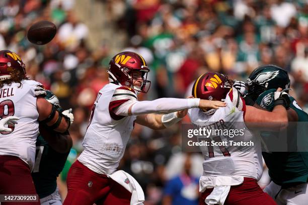 Quarterback Carson Wentz of the Washington Commanders fumbles the ball during the first half against the Philadelphia Eagles at FedExField on...